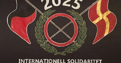 Målad banderoll med SUFs logga. En svartröd och en skånsk flagga korsas i mitten. Text på banderollen "Internationell solidaritet Skånska socialisters kampenhet".