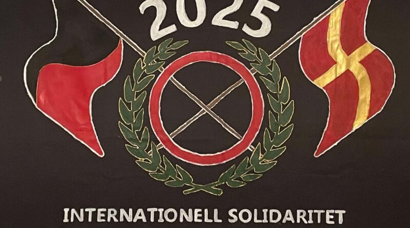 Målad banderoll med SUFs logga. En svartröd och en skånsk flagga korsas i mitten. Text på banderollen "Internationell solidaritet Skånska socialisters kampenhet".